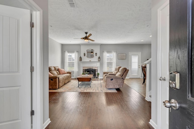 living room with hardwood / wood-style floors, ceiling fan, and a textured ceiling