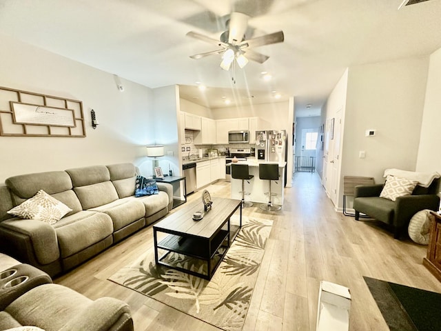 living room with ceiling fan and light hardwood / wood-style flooring