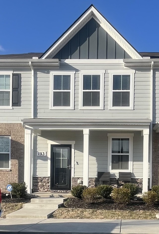 townhome / multi-family property with board and batten siding, stone siding, and a porch