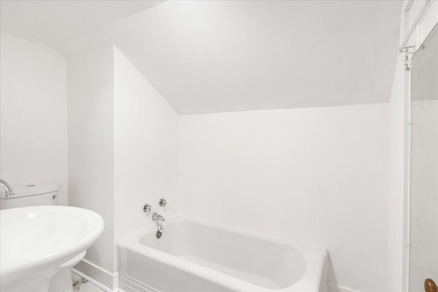 bathroom with a bathtub, lofted ceiling, and sink