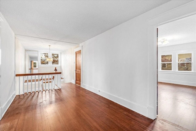 unfurnished room with hardwood / wood-style floors, a notable chandelier, and a textured ceiling