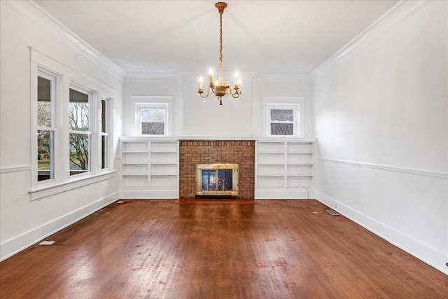 unfurnished living room with dark wood-type flooring, a brick fireplace, a chandelier, a textured ceiling, and ornamental molding