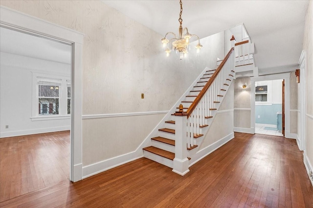 stairs with an inviting chandelier and hardwood / wood-style flooring