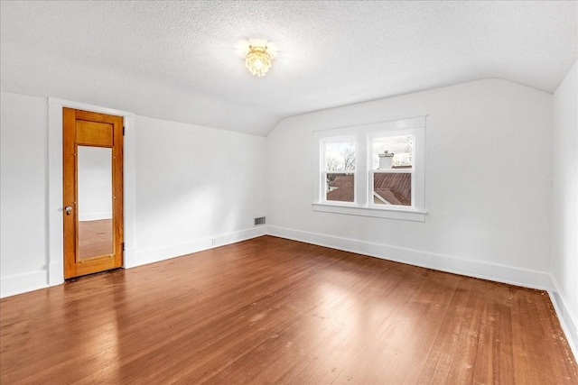 bonus room with wood-type flooring, a textured ceiling, and vaulted ceiling