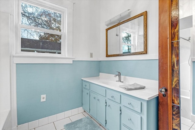 bathroom with tile patterned floors, plenty of natural light, vanity, and tile walls