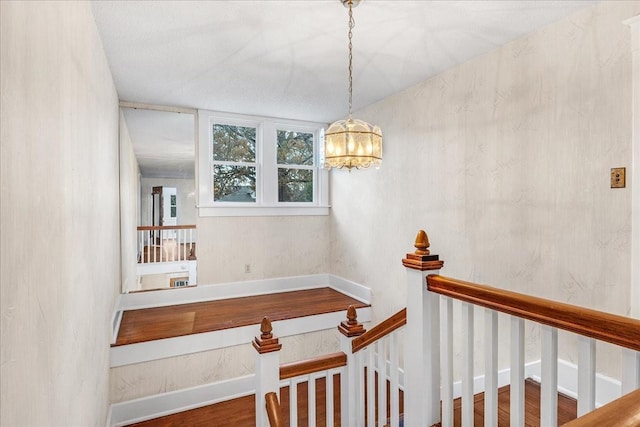 stairs with hardwood / wood-style floors and a chandelier