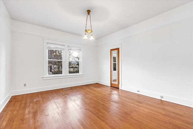 unfurnished room featuring hardwood / wood-style flooring and an inviting chandelier