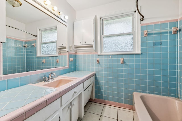 bathroom featuring tile patterned flooring, vanity, tiled shower / bath combo, and tile walls