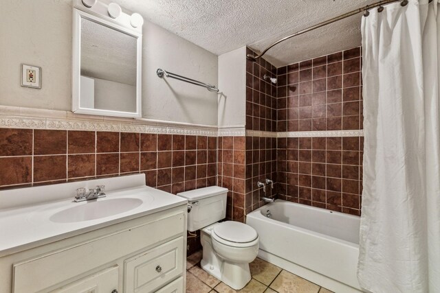 full bathroom featuring vanity, tile patterned flooring, shower / bathtub combination with curtain, tile walls, and a textured ceiling