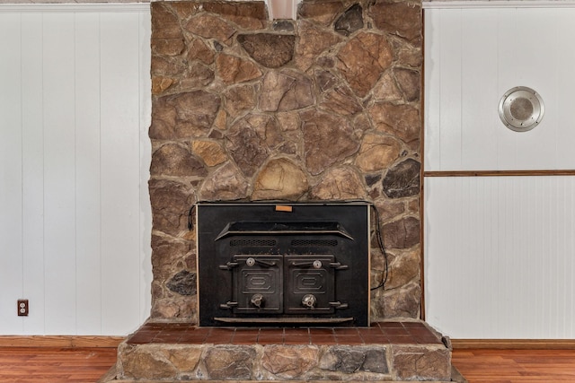 details featuring hardwood / wood-style floors, a wood stove, and wood walls