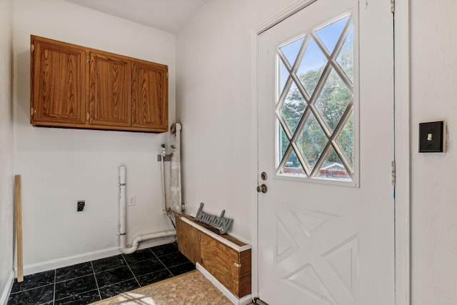 laundry area featuring hookup for an electric dryer, cabinets, and dark tile patterned floors