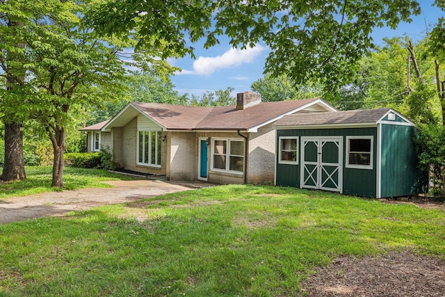 ranch-style house featuring a front yard and a storage unit