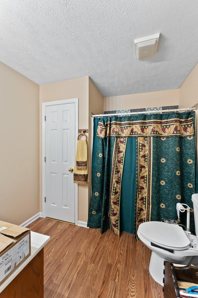 bathroom featuring toilet, a textured ceiling, and hardwood / wood-style flooring