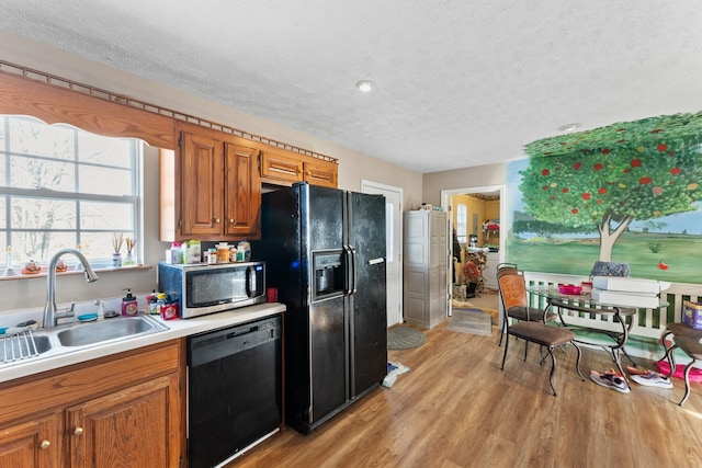 kitchen featuring black appliances, light wood-type flooring, sink, and a textured ceiling