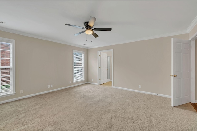 carpeted spare room with ceiling fan, crown molding, and a wealth of natural light