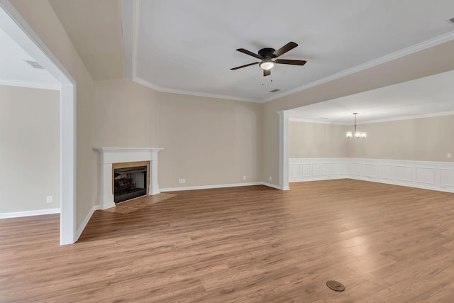 unfurnished living room with light wood-type flooring, ceiling fan with notable chandelier, and ornamental molding