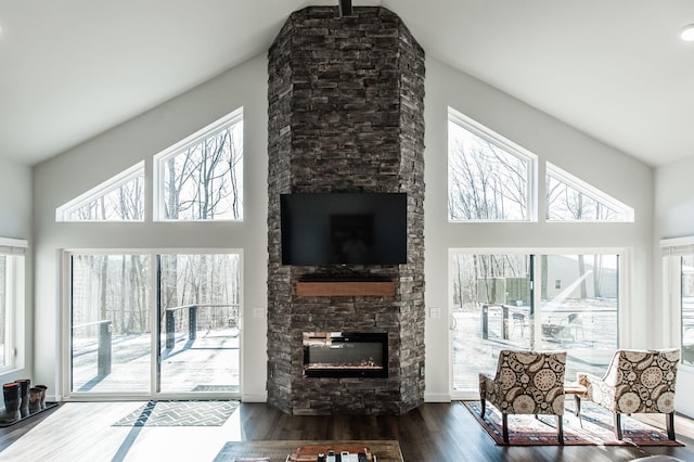 living room with a towering ceiling, dark hardwood / wood-style floors, and a stone fireplace