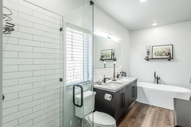 bathroom with wood-type flooring, vanity, a tub, decorative backsplash, and toilet