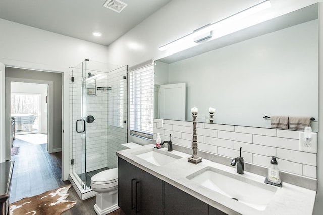 bathroom featuring toilet, vanity, backsplash, hardwood / wood-style flooring, and an enclosed shower