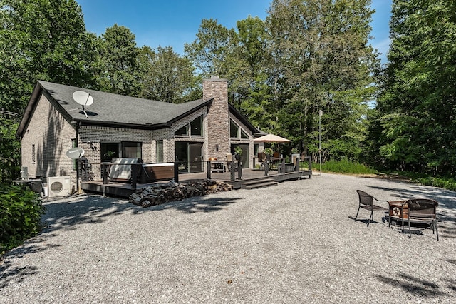 rear view of house featuring an outdoor fire pit, ac unit, a hot tub, and a wooden deck