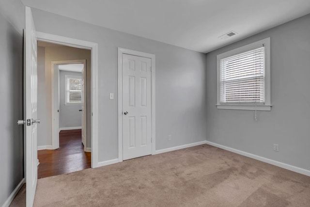 unfurnished bedroom with a closet and light colored carpet