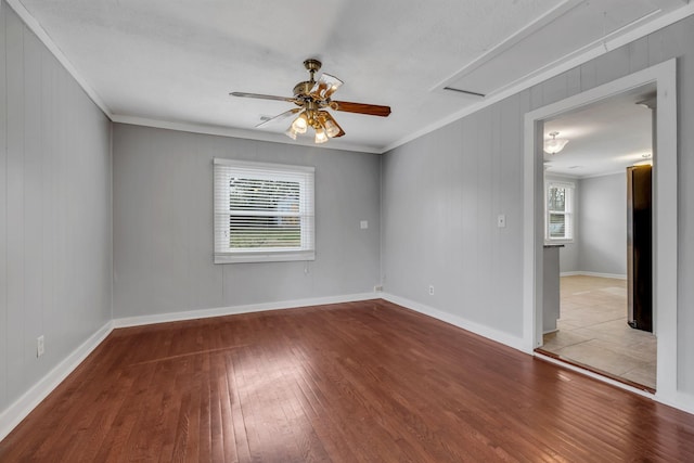 spare room with ceiling fan, light wood-type flooring, crown molding, and wooden walls