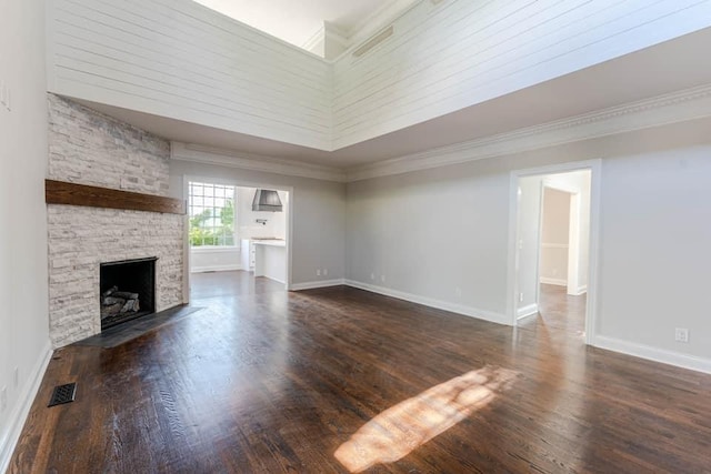 unfurnished living room with dark hardwood / wood-style floors, crown molding, a towering ceiling, and a fireplace