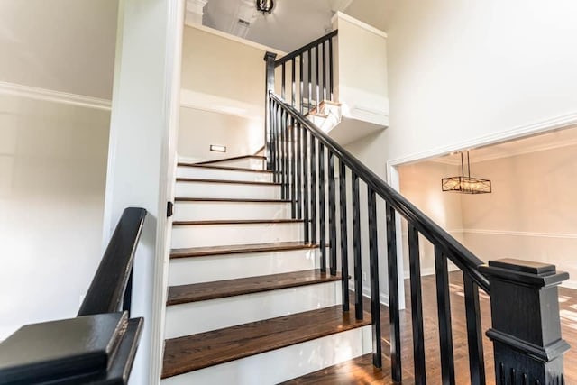 stairway featuring hardwood / wood-style floors and ornamental molding