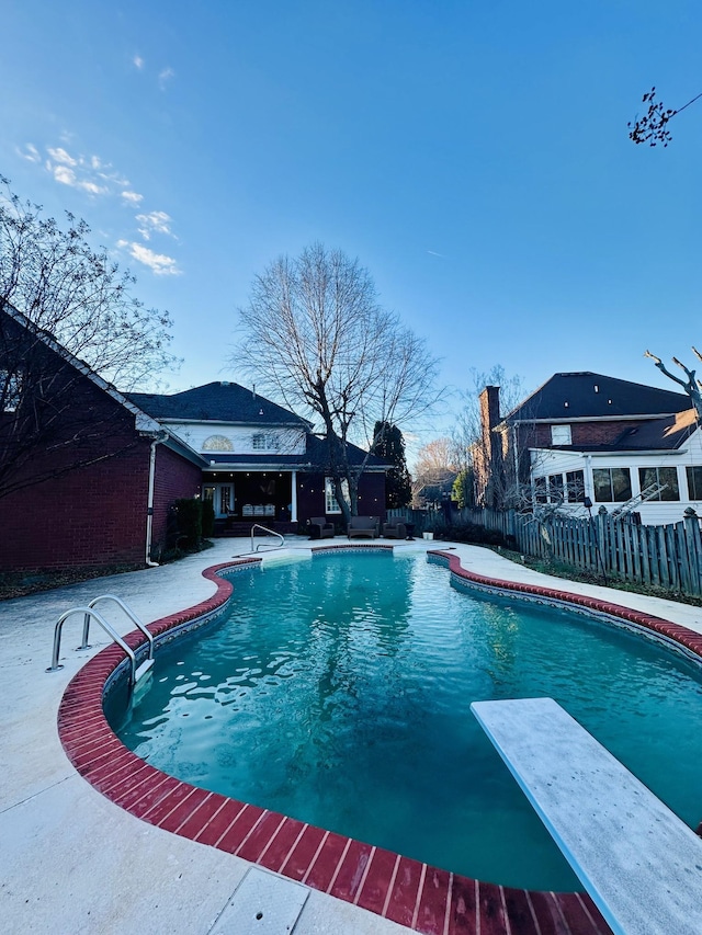 view of swimming pool featuring a diving board and a patio