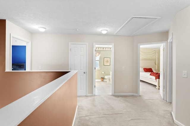 hallway with light colored carpet and a textured ceiling