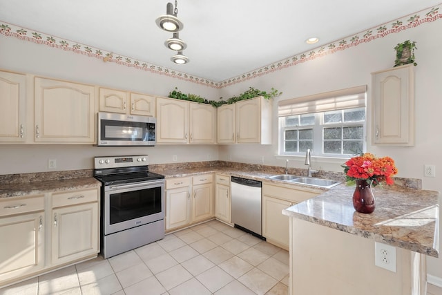 kitchen featuring sink, stainless steel appliances, kitchen peninsula, cream cabinetry, and light tile patterned flooring