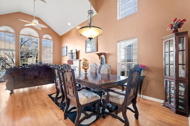 dining space featuring ceiling fan, high vaulted ceiling, and light wood-type flooring