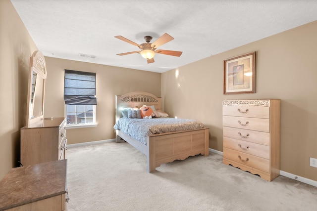 bedroom with ceiling fan, light colored carpet, and a textured ceiling