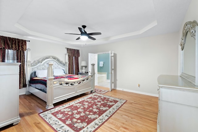 bedroom with wood-type flooring, a tray ceiling, and ceiling fan