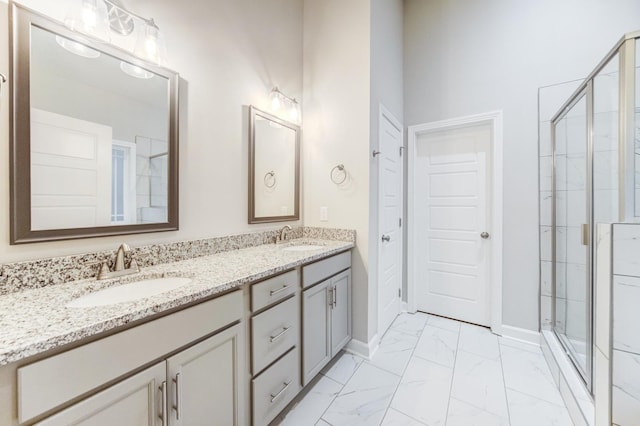 full bath with double vanity, marble finish floor, a shower stall, and a sink