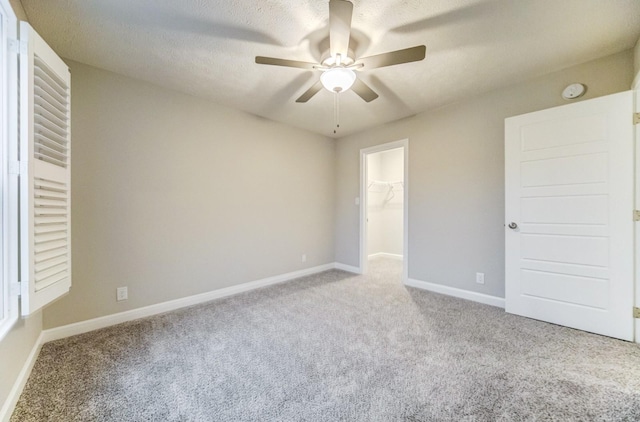 unfurnished room with ceiling fan, carpet floors, a textured ceiling, and baseboards