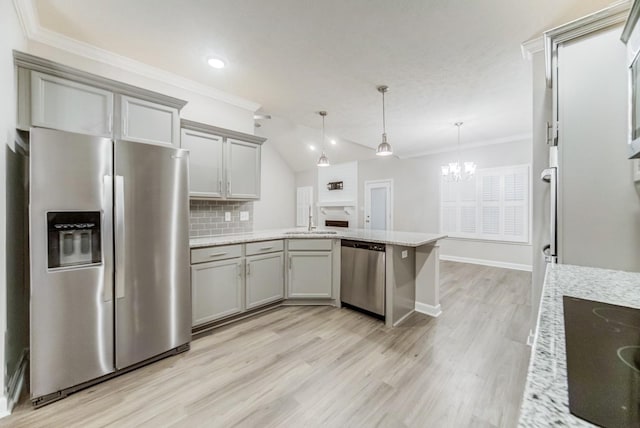 kitchen featuring appliances with stainless steel finishes, a peninsula, crown molding, gray cabinetry, and a sink