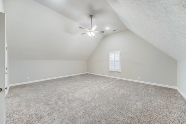 bonus room featuring baseboards, ceiling fan, vaulted ceiling, a textured ceiling, and carpet flooring