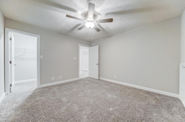 empty room with ceiling fan, a textured ceiling, carpet flooring, and baseboards