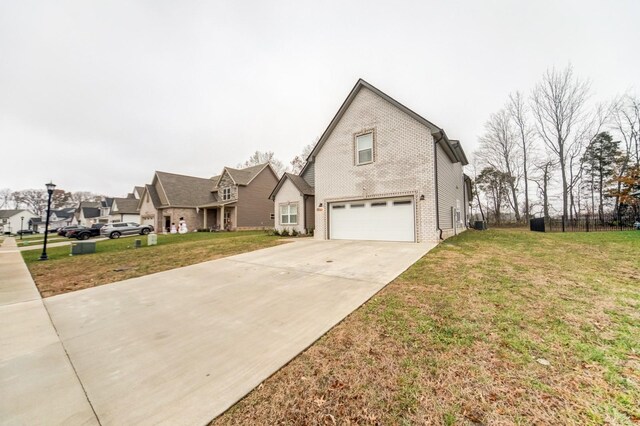 traditional-style home featuring a garage, driveway, a front yard, and brick siding