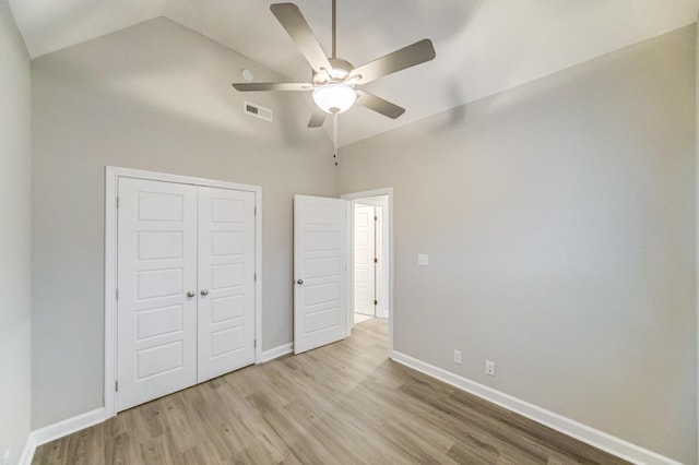 unfurnished bedroom with lofted ceiling, a closet, ceiling fan, wood finished floors, and baseboards