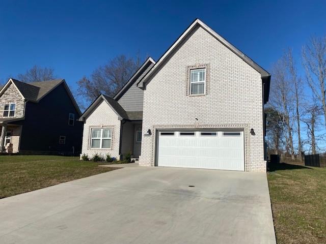 traditional-style house with a garage, concrete driveway, brick siding, and a front lawn