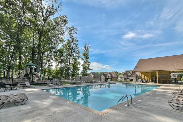 community pool featuring a patio area, fence, and playground community