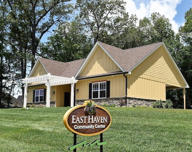 view of front of house featuring board and batten siding, a front yard, stone siding, and roof with shingles