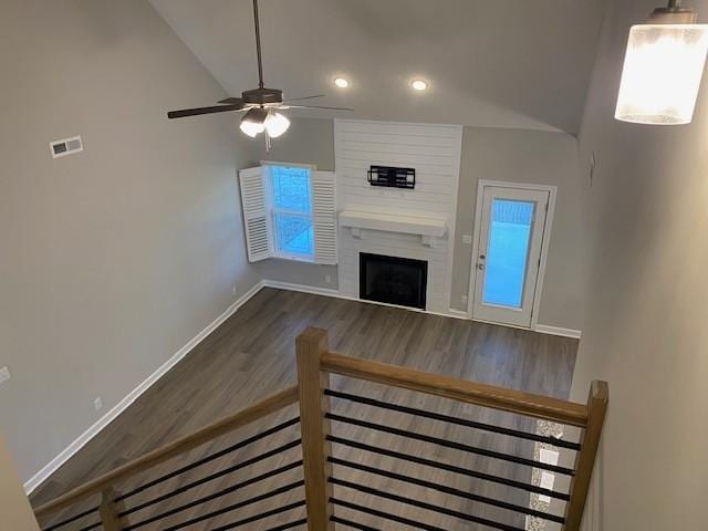 unfurnished living room with visible vents, a large fireplace, ceiling fan, wood finished floors, and baseboards