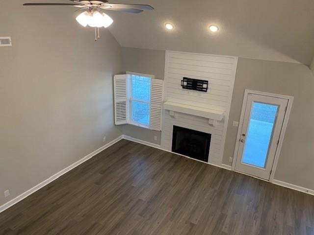 unfurnished living room with lofted ceiling, a large fireplace, dark wood-type flooring, a ceiling fan, and baseboards