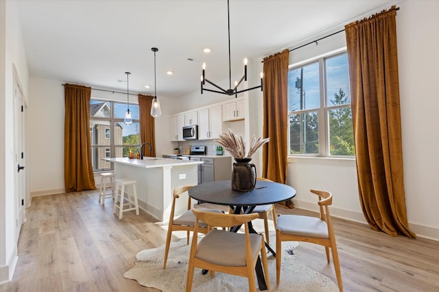 dining area featuring light hardwood / wood-style floors, a wealth of natural light, a notable chandelier, and sink