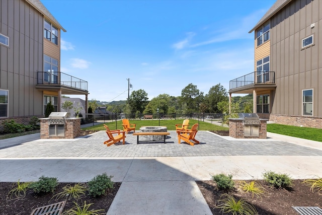 view of patio / terrace featuring a grill, a balcony, an outdoor fire pit, and exterior kitchen