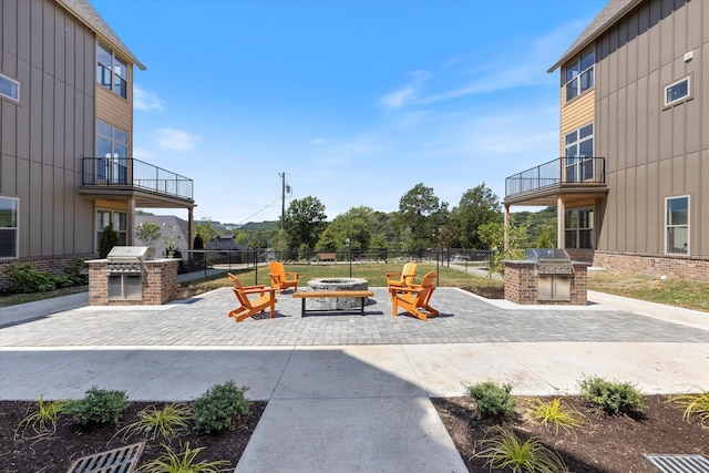 view of patio featuring grilling area, a balcony, exterior kitchen, and an outdoor fire pit