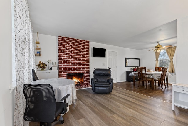 living room featuring hardwood / wood-style flooring, a brick fireplace, and ceiling fan